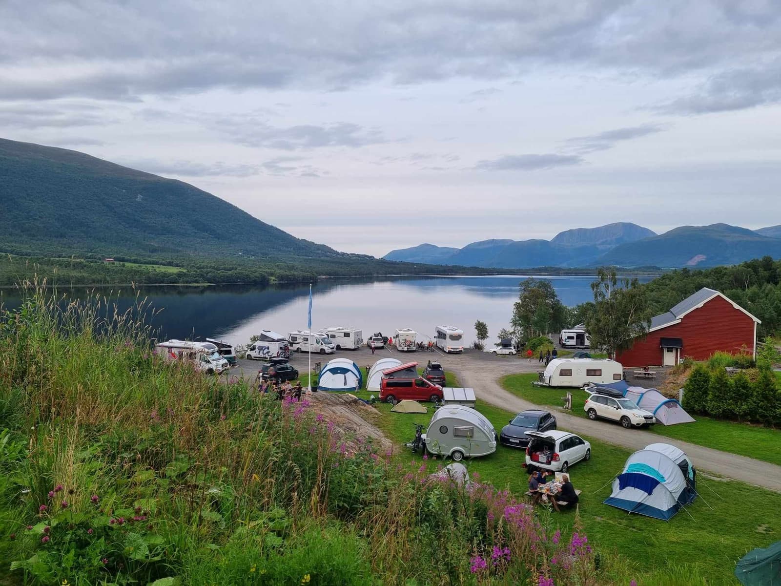 Der Campingplatz am Ufer mit Wohnwagen, Zelten und Autos