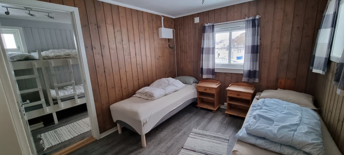 Schlafzimmer in Hütte 1 mit Etagenbett, Betten und Nachttischen