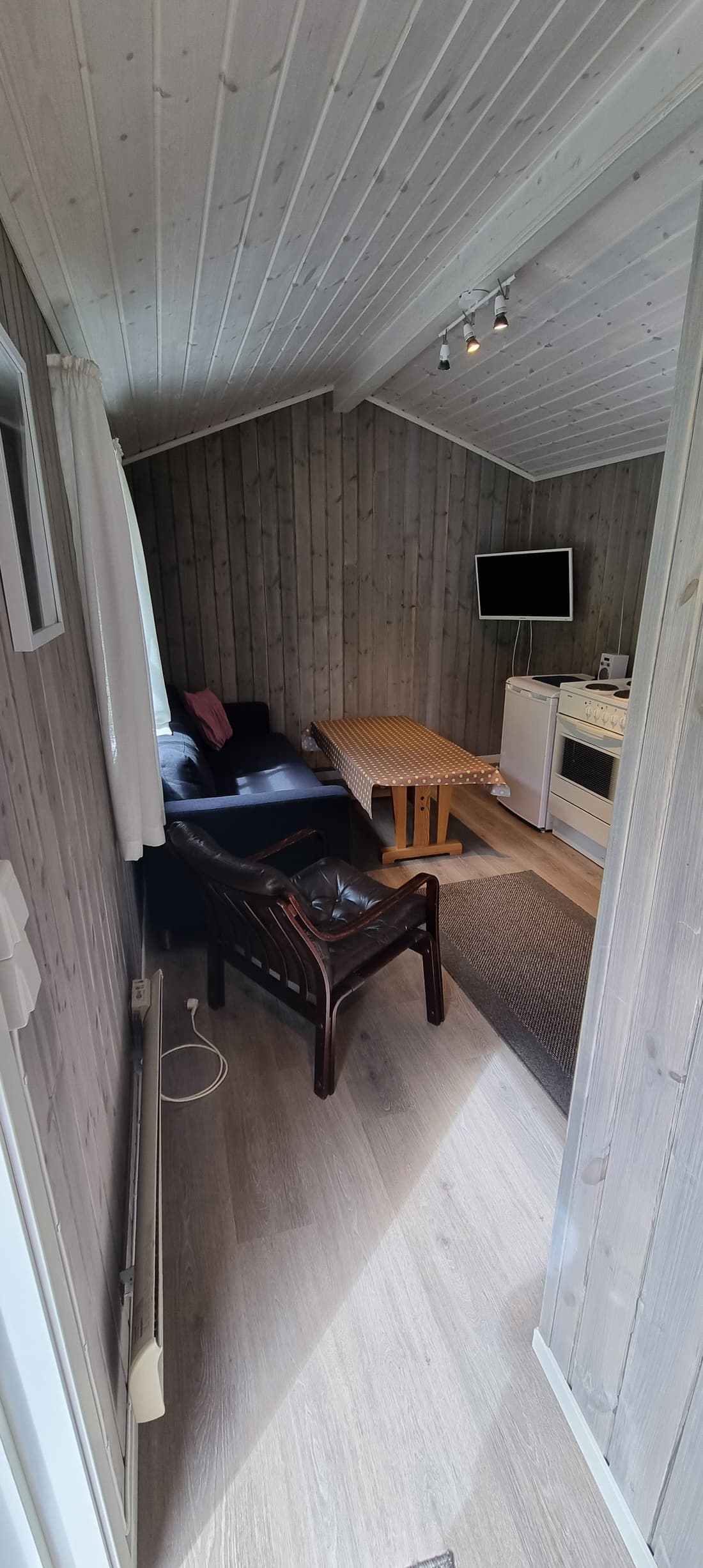 Wohnraum in Hütte 2 mit Sofa, Tisch und Fernseher unter der Dachschräge