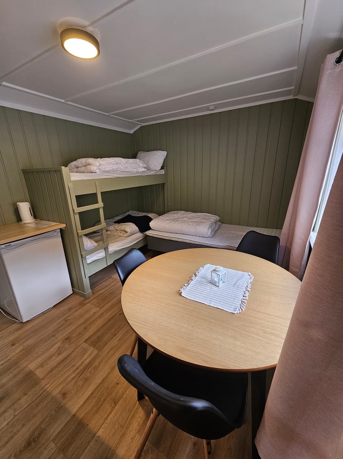 Innenraum von Hütte 4 mit Etagenbett, Esstisch und grüner Verkleidung