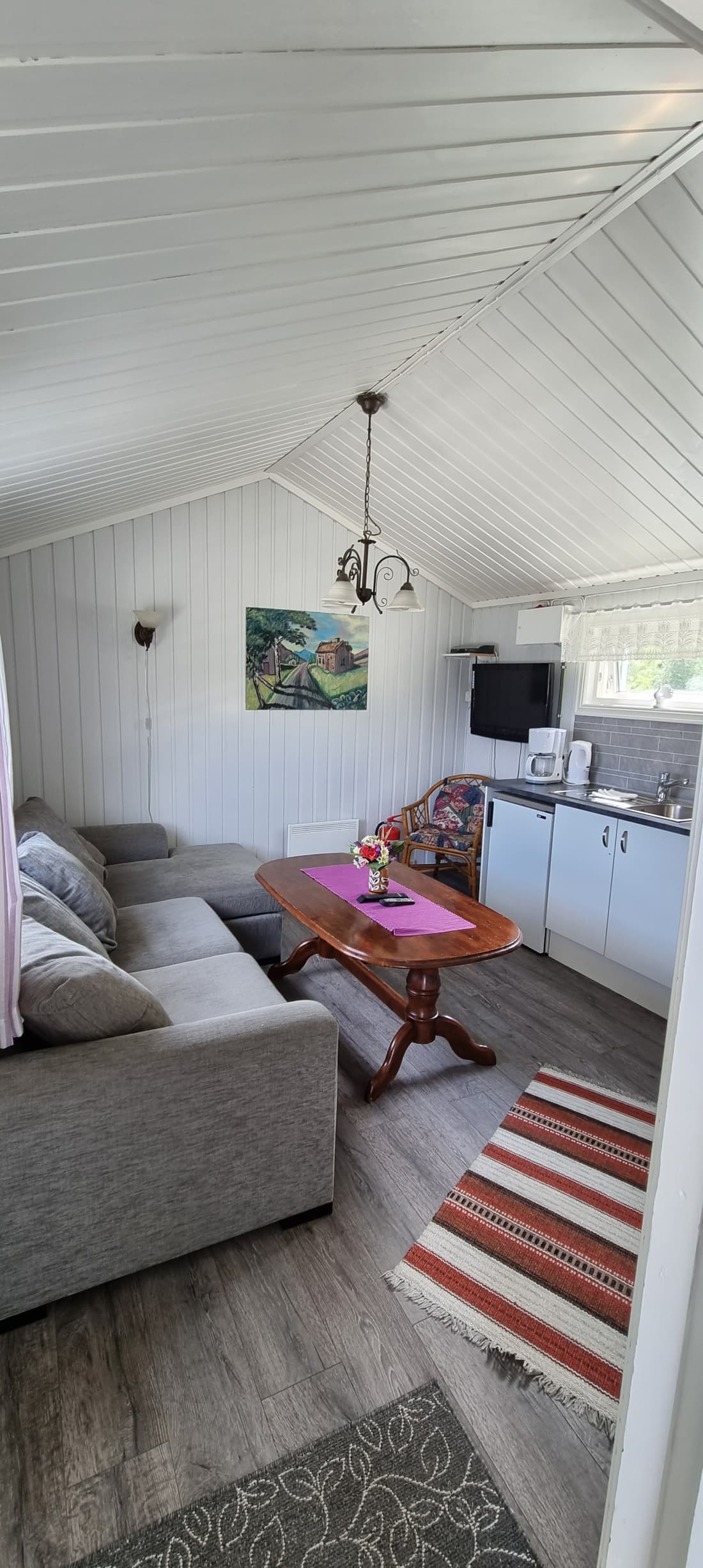 Wohnraum in Hütte 6 mit Sofa, Tisch und offener Küche dahinter