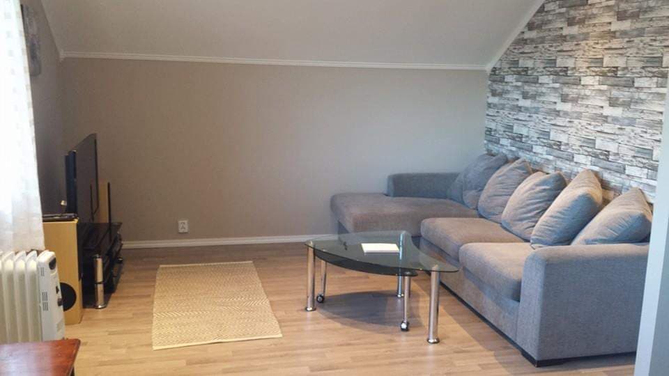 Wohnzimmer der Wohnung mit Sofa, Couchtisch und Natursteinwand