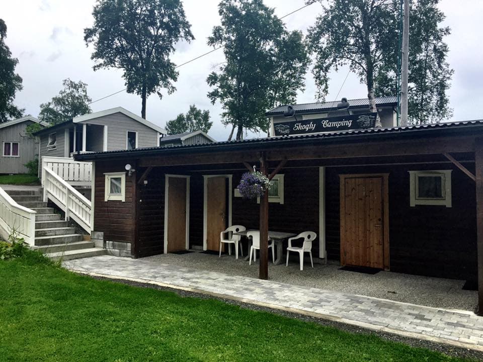 Overbygd uteplass med bord, stoler og hengende blomsterkorger