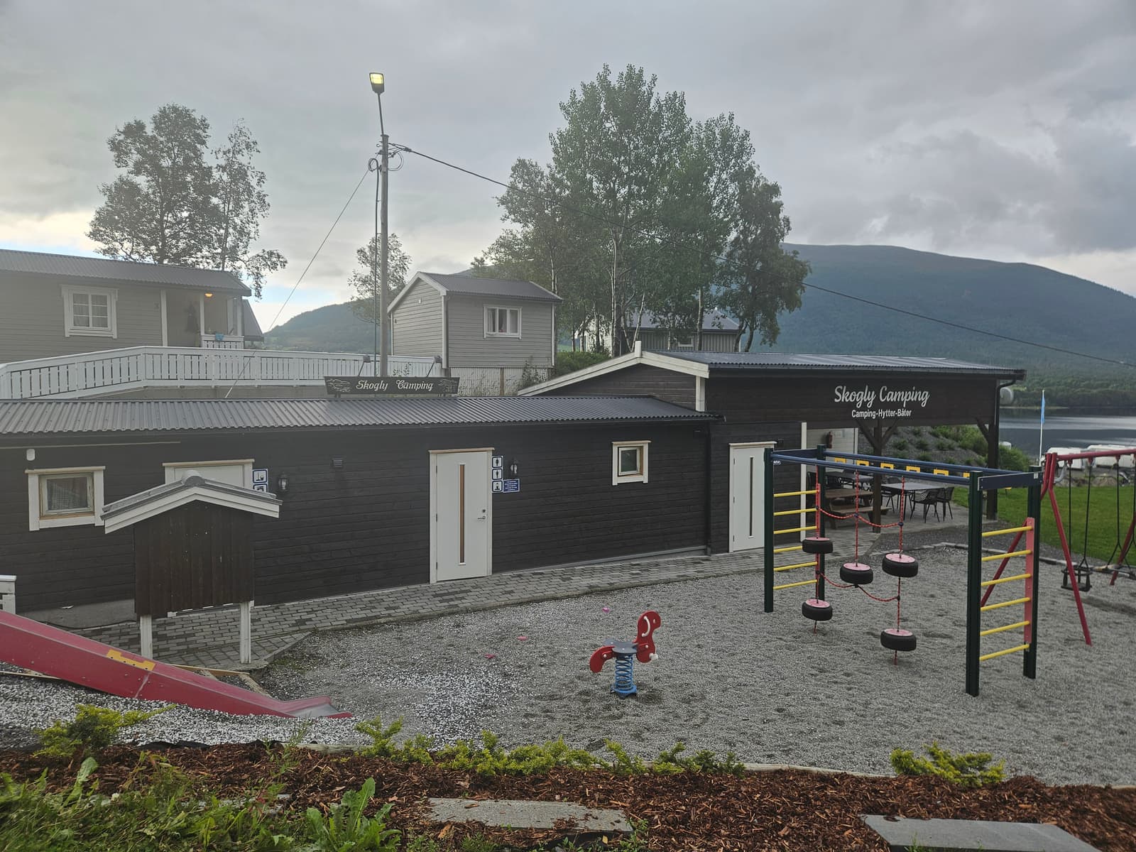 Servicebygget med skiltet Skogly Camping og lekeplassen foran